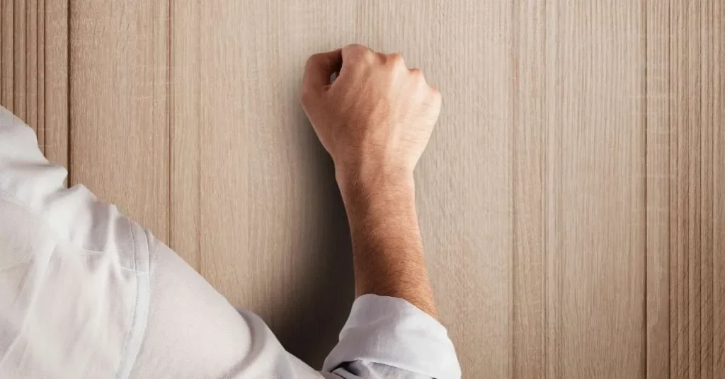 Hand, die auf Holz klopft