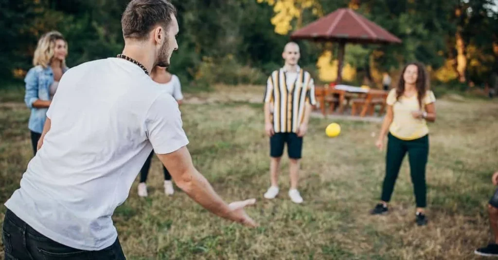 Personen stehen im Kreis und werfen sich einen Ball zu