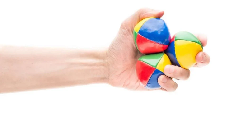 Hand hält drei Jonglierbälle