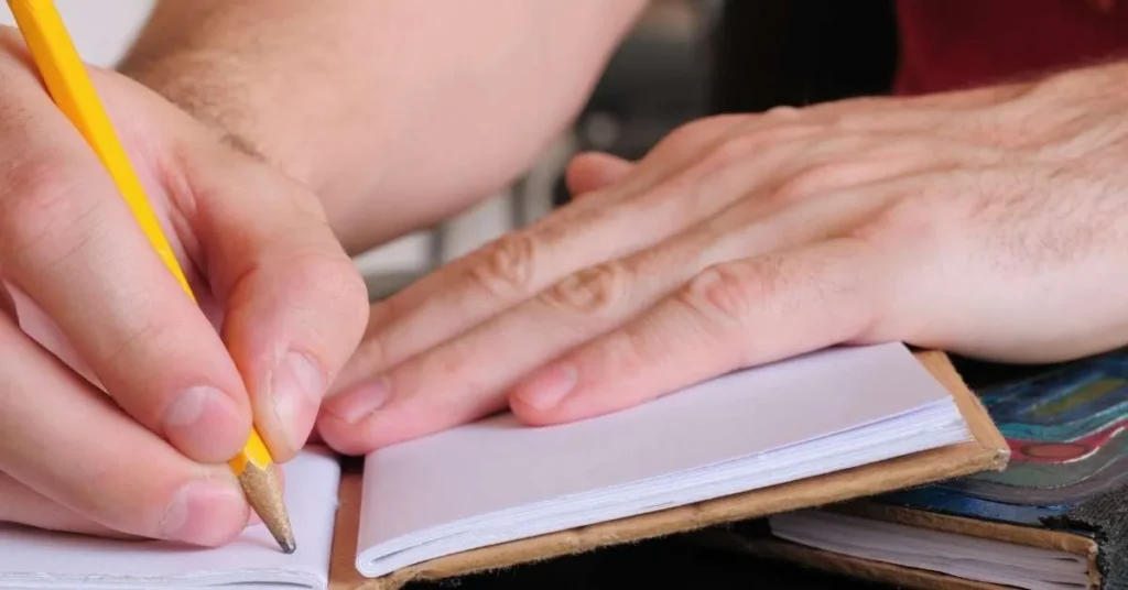 Person schreibt mit Bleistift in ein Heft